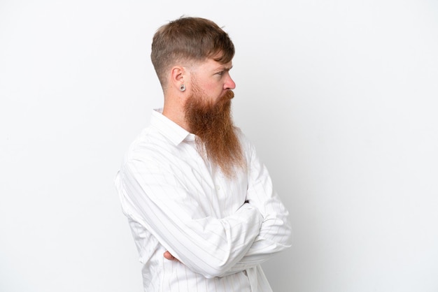 Homem ruivo com barba longa, isolado no fundo branco, mantendo os braços cruzados