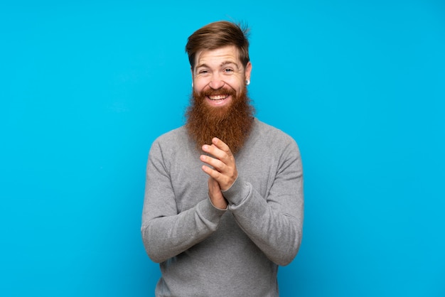 Homem ruivo com barba longa sobre aplaudindo azul isolado após apresentação em uma conferência