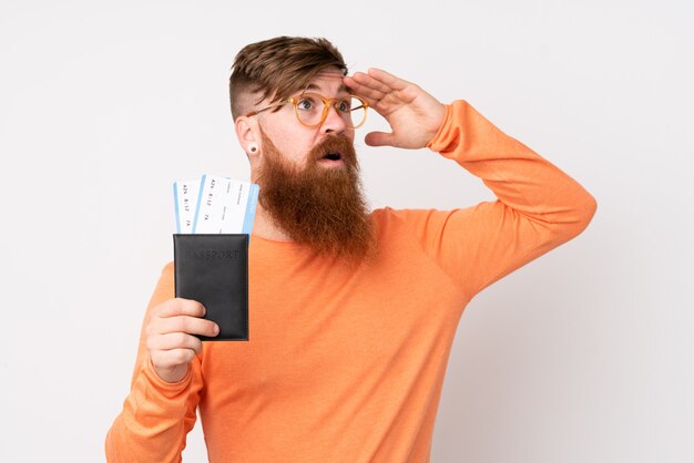 Homem ruivo com barba longa sobre branco isolado em férias com bilhetes de avião e passaporte enquanto olha algo à distância