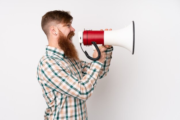 Foto homem ruivo com barba longa sobre parede branca isolada, gritando através de um megafone