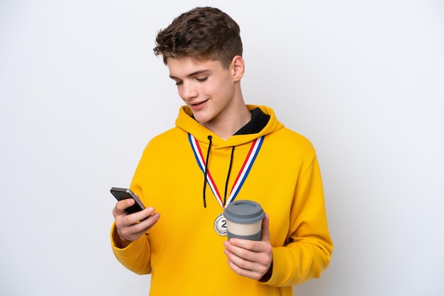 Homem russo adolescente com medalhas isoladas em fundo branco segurando café para levar e um celular