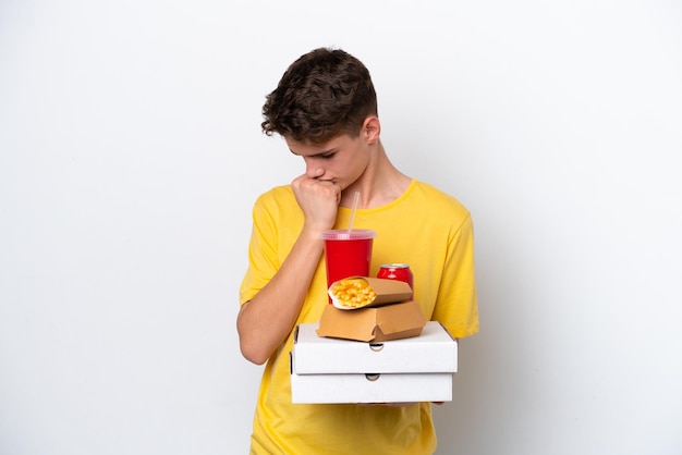 Homem russo adolescente segurando fast food isolado no fundo branco com dúvidas