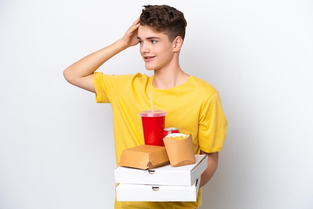Homem russo adolescente segurando fast food isolado no fundo branco sorrindo muito