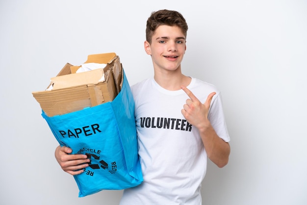 Homem russo adolescente segurando um saco de reciclagem cheio de papel para reciclar isolado no fundo branco, dando um polegar para cima gesto