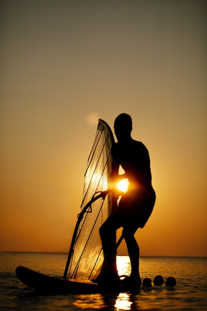 Homem, sailboarding, em, pôr do sol