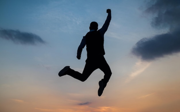 Homem salta silhueta alta cheia de energia contra a energia do céu do pôr do sol