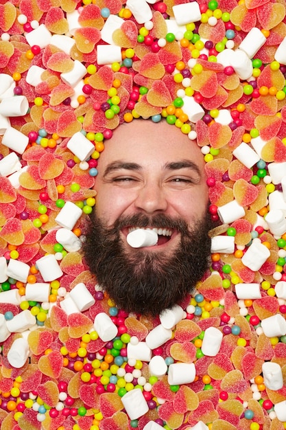 Foto homem satisfeito em doces mordendo marshmallow