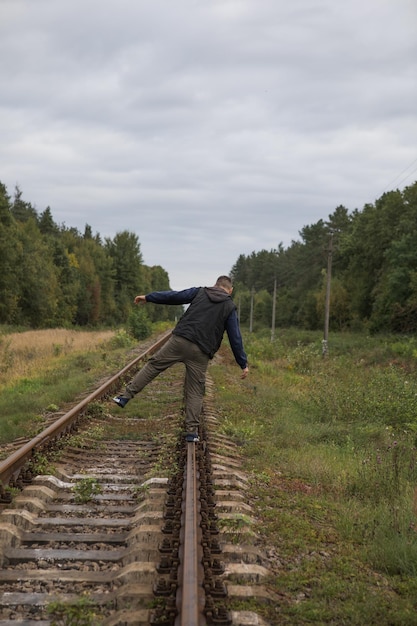 Homem se afasta na ferrovia com luz quente Viajante na ferrovia