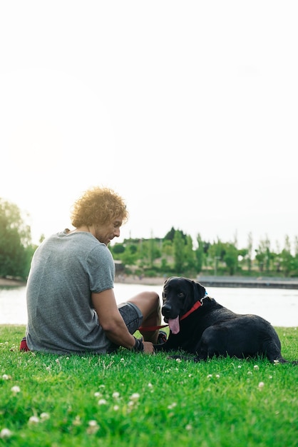 Foto homem se divertindo e brincando com seu cachorro no parque.