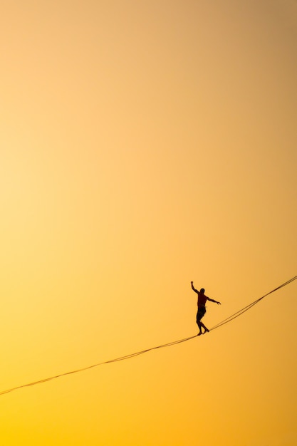 Homem se equilibrando em uma corda contra o céu