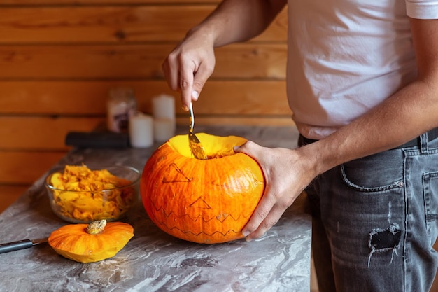 Homem se prepara para o Halloween esculpindo abóbora closeup