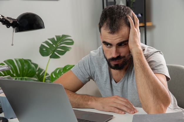 Foto homem se sentindo cansado enquanto trabalhava em casa no laptop