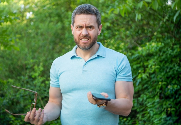 Homem se sentindo indignado segurando celular expressando indignação homem com telefone tendo indignação