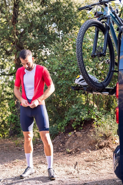 Foto homem se vestindo ao lado de sua van para andar de bicicleta