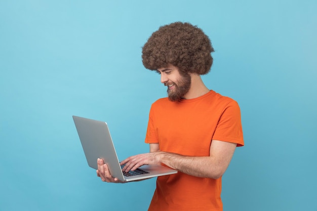 Homem segura laptop na mão e digitando blogueiro fazendo postagens em redes sociais conversando com seguidores