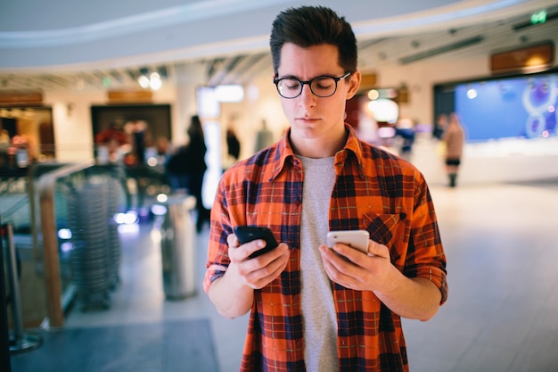 Homem segura o smartphone no shopping