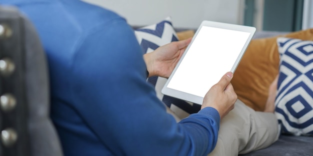 homem segura tablet digital com maquete de tela branca em branco isolada para brincar na sala de estar em casa