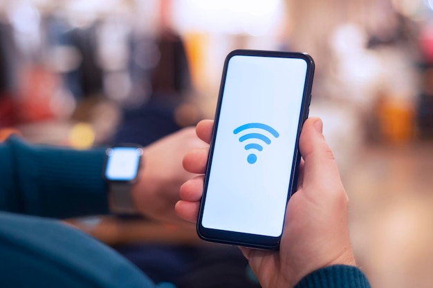 Homem segura um smartphone com um ícone de wifi closeup e um relógio inteligente na mão