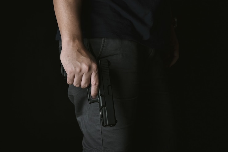 Foto homem segurando a arma perto do corpo, assassino com pistola de 9mm à espera de roubar a vítima
