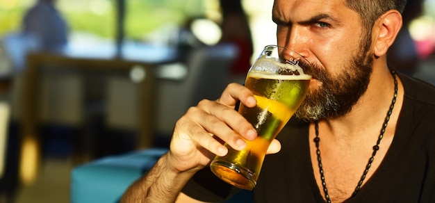 Homem segurando a caneca de cerveja homem barbudo sexy sorriso aberto e grande caneca de cerveja na mão cara no bar c