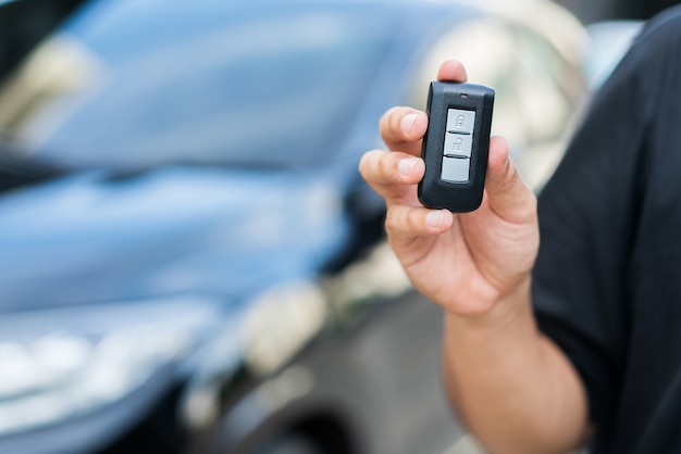 Homem segurando a chave do carro remoto em pé perto de seu carro