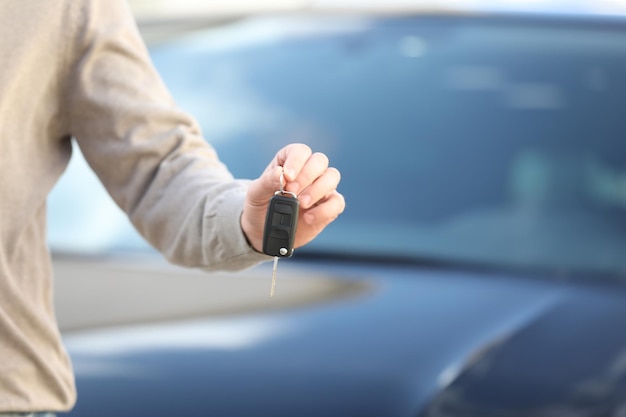 Homem segurando a chave em uma concessionária de automóveis moderna comprando carro novo