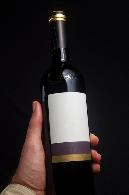 Homem segurando a garrafa de vinho tinto isolada no rótulo de maquete de fundo preto