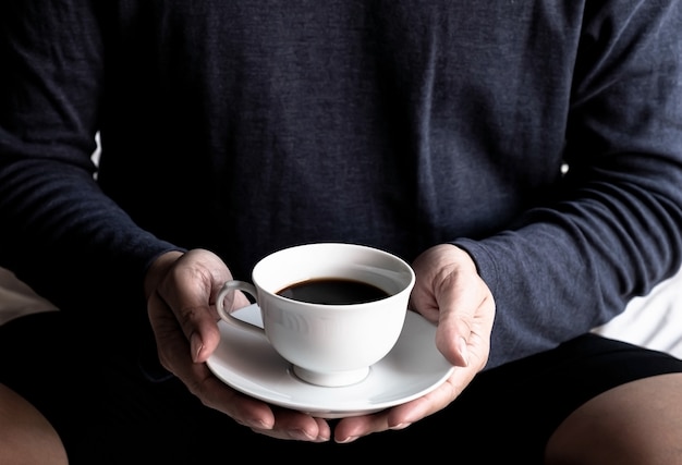 Homem segurando a mão em uma xícara de café.