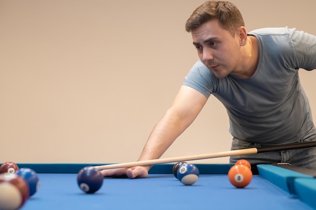 Homem segurando a mão na mesa de bilhar jogando sinuca ou se preparando para atirar bolas de bilhar sinuca