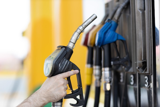 Homem segurando a pistola de enchimento na mão no posto de gasolina