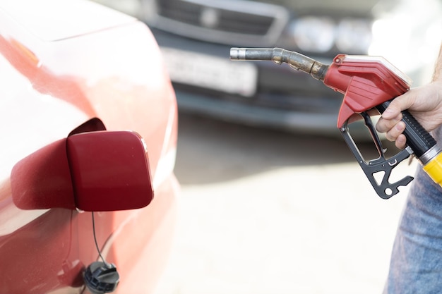 Foto homem segurando a pistola de enchimento na mão no posto de gasolina