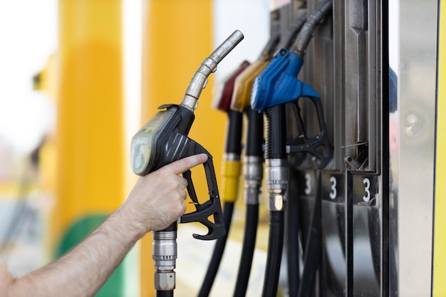 Homem segurando a pistola de enchimento na mão no posto de gasolina