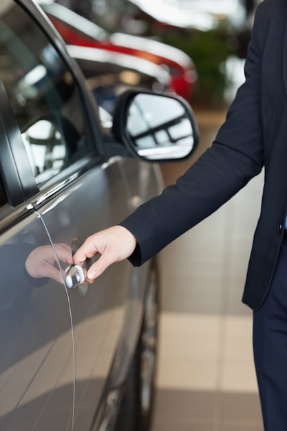 Homem segurando as alças de uma porta de carro