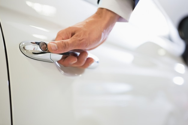 Homem segurando as alças de uma porta de carro