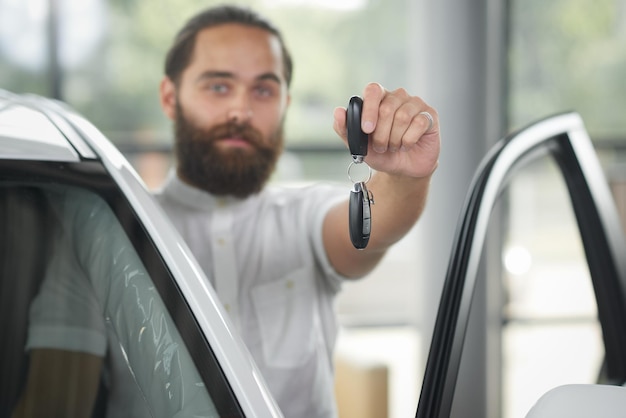 Homem segurando as chaves do carro no showroom de carros