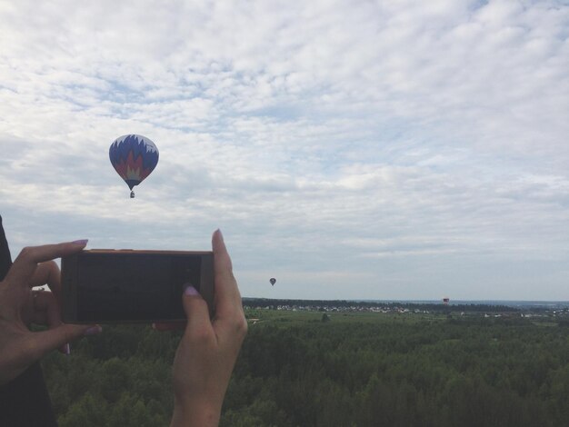 Foto homem segurando balão de ar quente voando sobre o mar contra o céu