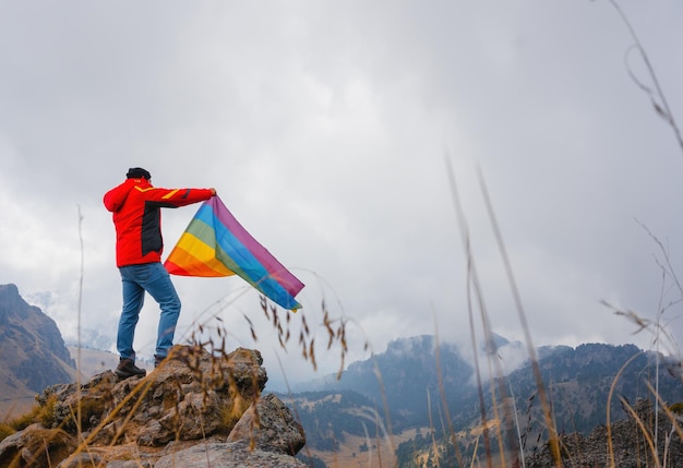 Homem segurando bandeira do orgulho gay na montanha