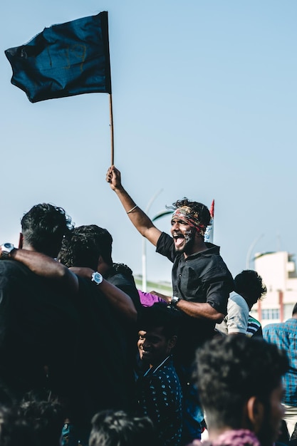 Homem segurando bandeira enquanto grita contra o céu