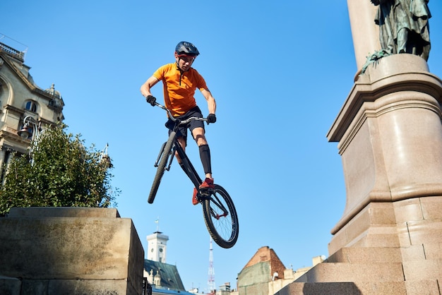 Homem segurando bicicleta esportiva e pendurado no ar