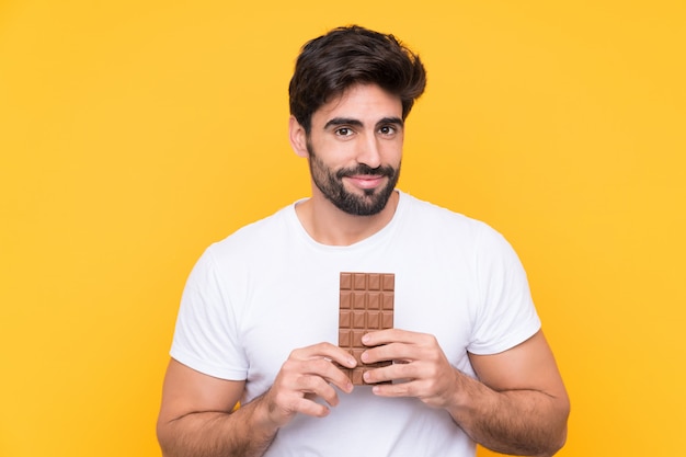 Homem segurando chocolate sobre parede isolada