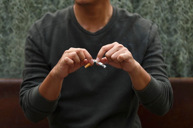 Homem segurando cigarro quebrado nas mãos Pare de fumar conceito de cigarros Conceito de campanha sem fumar