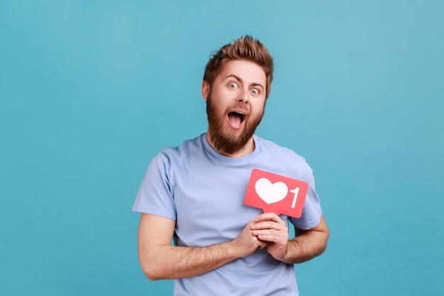 Homem segurando coração de mídia social como botão na frente de sua notificação de seguidor de emoji de peito