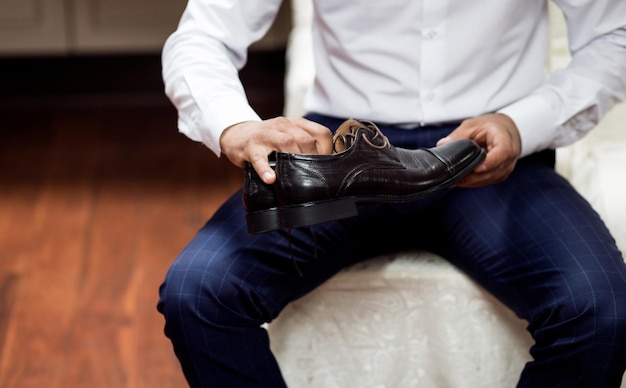 Homem segurando elegantes sapatos pretos nas mãos irreconhecível
