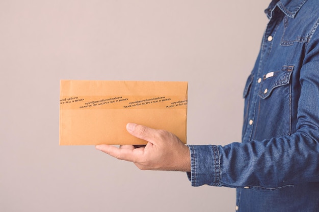 Homem segurando envelope confidencial marrom lacrado com fita adesiva e palavra por favor, não aceite se o selo estiver quebrado em tailandês e inglês