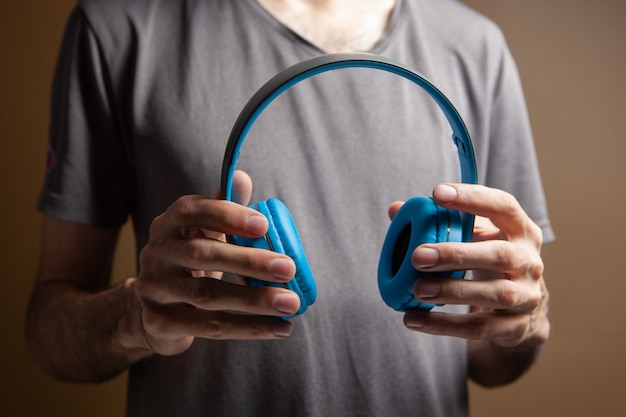 Homem segurando fones de ouvido em fundo marrom