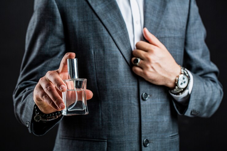 Foto homem segurando frasco de perfume. entregue com relógio de pulso em um terno de negócio.
