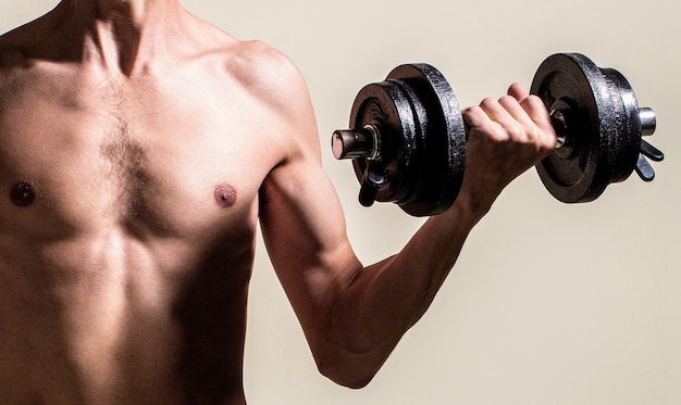 Homem segurando halteres na mão. Cara magro segura halteres nas mãos. Um homem magro praticando esportes com halteres