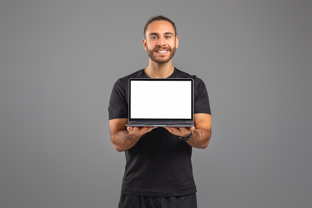 Homem segurando laptop com tela branca em fundo cinza