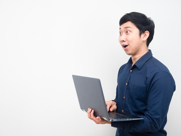 Homem segurando laptop se sentindo surpreso ao olhar para o copy sapce