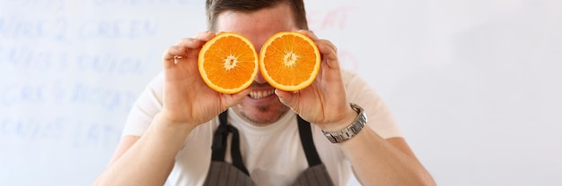 Homem segurando laranjas cortadas ao nível dos olhos em vez de óculos